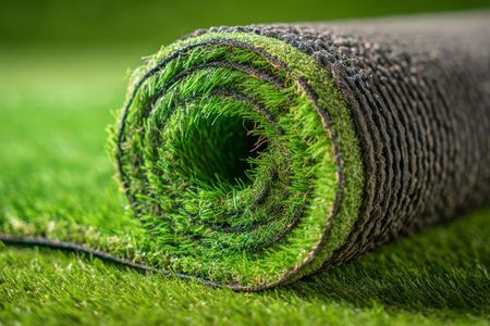 Un rollo de césped artificial se encuentra encima de un exuberante campo verde.