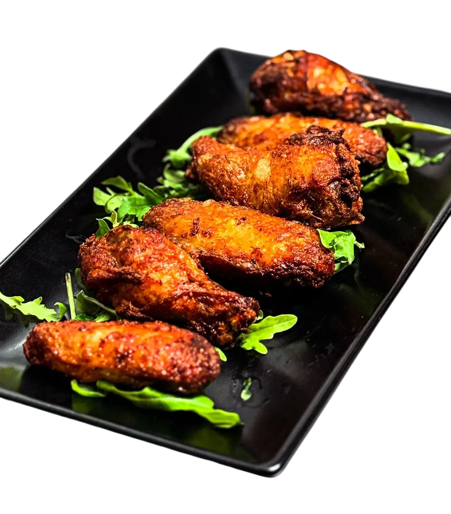 Plato negro con cuatro alitas de pollo fritas picantes adornadas con hierbas verdes.