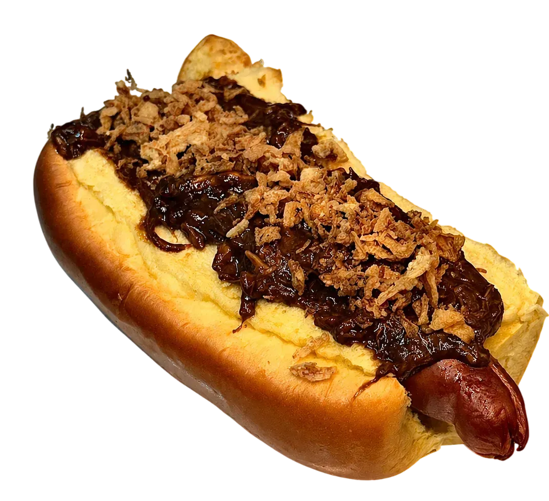 Perrito caliente cubierto con chili, queso rallado y cebolla crujiente en un panecillo.