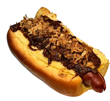 Perrito caliente cubierto con chili, queso rallado y cebolla crujiente en un panecillo.