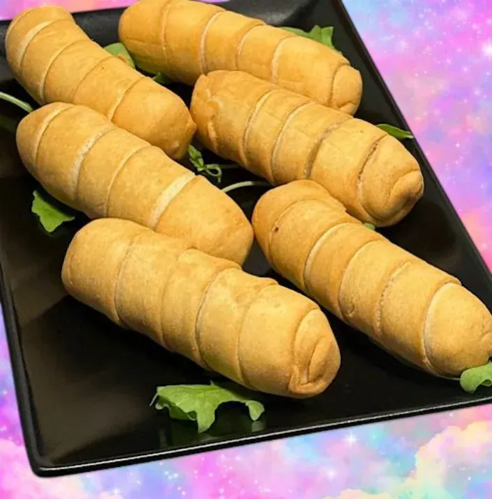 Bandeja de bocadillos empanizados fritos y dorados sobre un plato negro, adornados con lechuga.