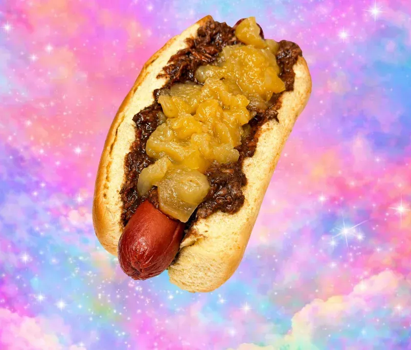 Perrito caliente cubierto con chucrut sobre un fondo rosa brillante.