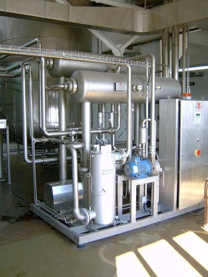 Industriemaschinen aus Edelstahl mit Rohren und Tanks, wahrscheinlich für die Lebensmittelverarbeitung.