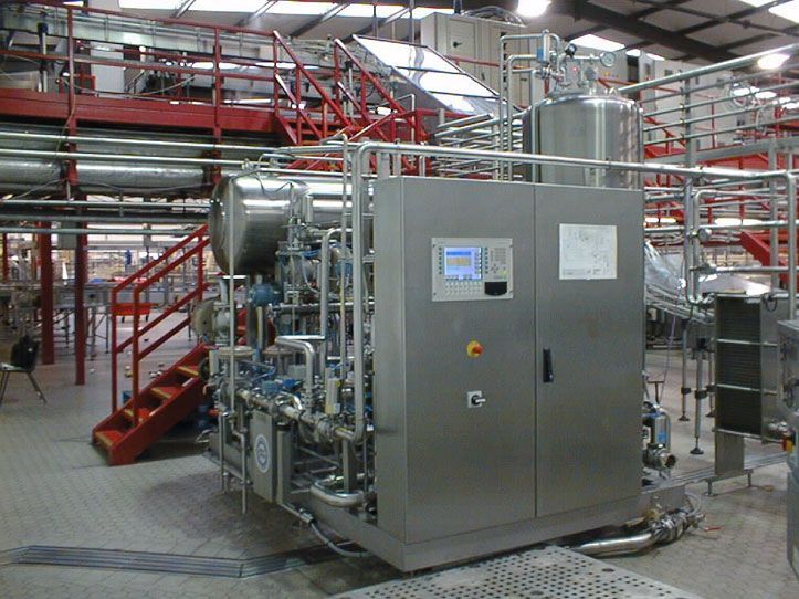 Industrielle Lebensmittelverarbeitungsmaschinen aus Edelstahl mit roten Rohrleitungen, Bedienfeld und Zugangstreppe.