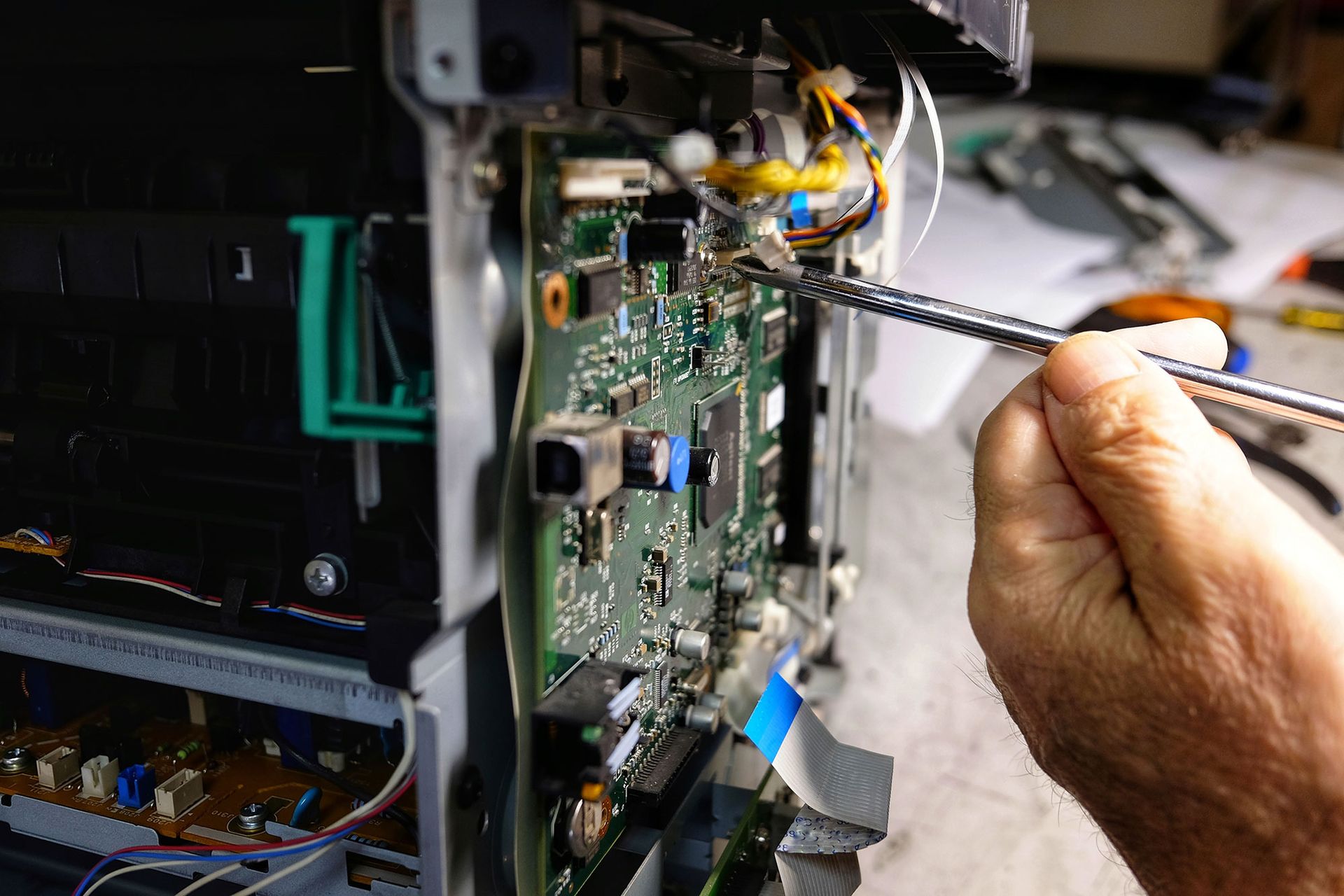 Eine Person repariert mit einem Schraubendreher eine Platine im Inneren eines Druckers.