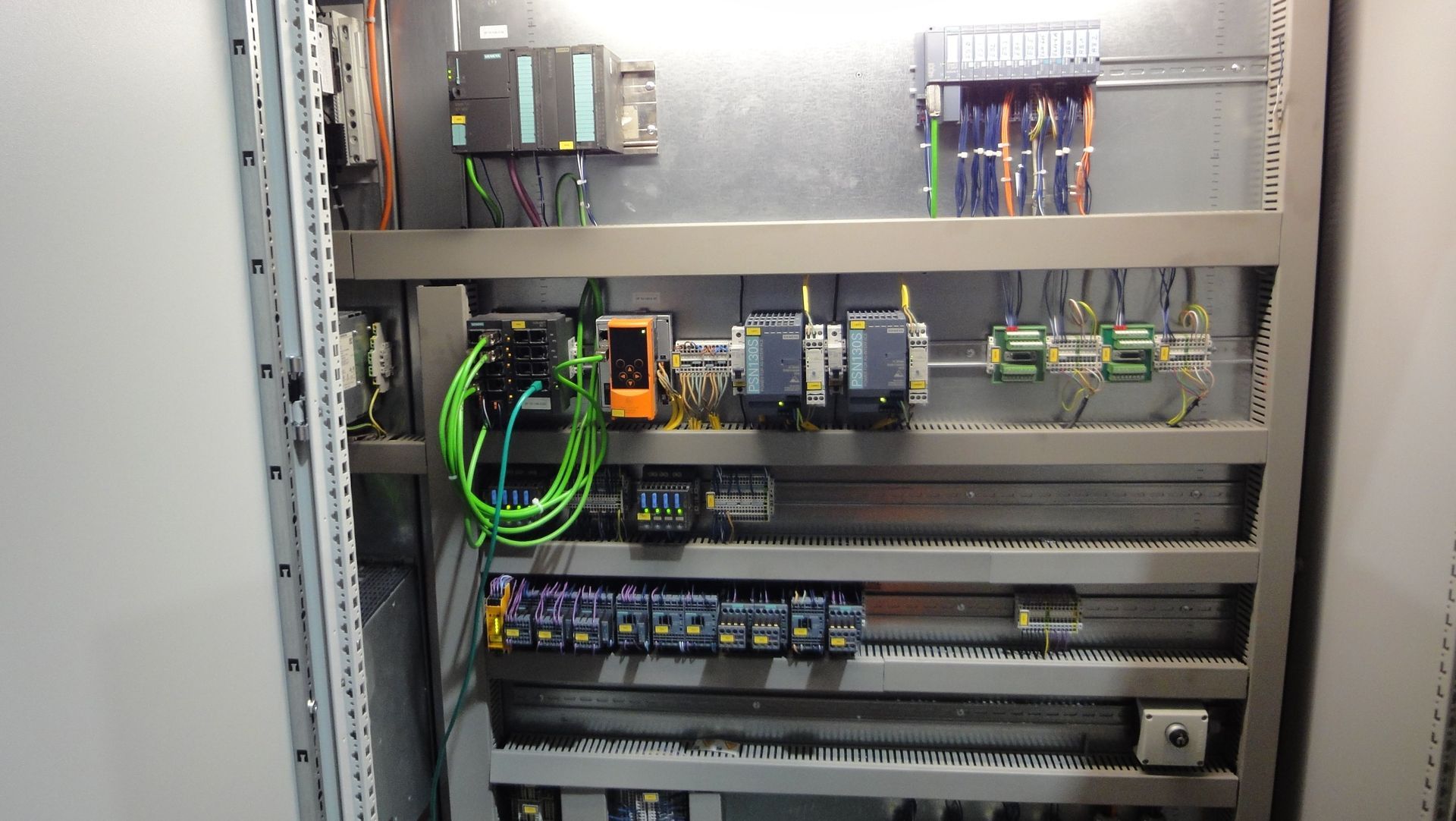 Innenraum des Schaltschranks mit verschiedenen elektrischen Bauteilen, Kabeln und einer SPS.
