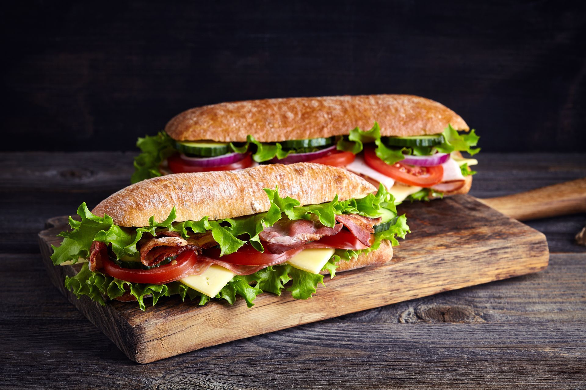 Des sandwichs garnis de crudités et de viande sur une planche.