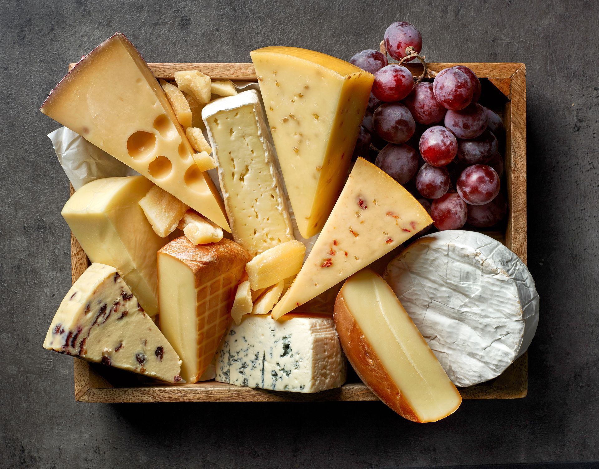 Un panier de fromages avec des raisins.