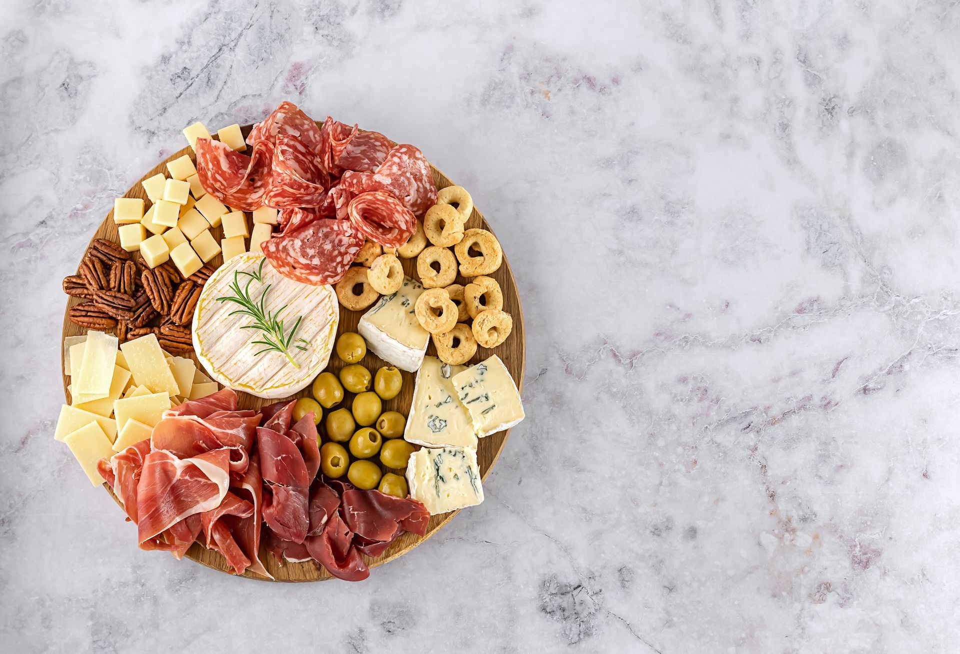 Une planche de charcuteries et de fromages variés sur du marbre.