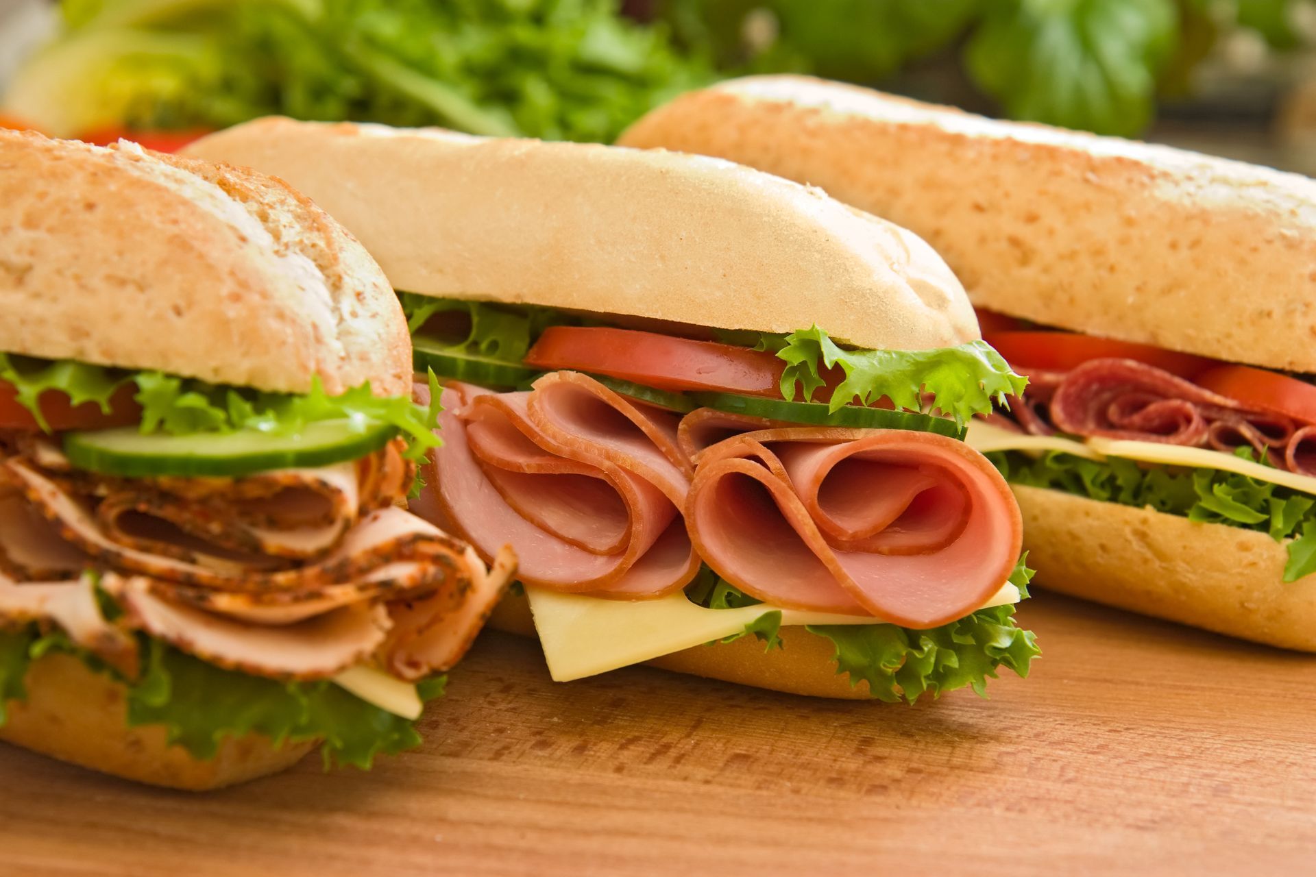 Des sandwichs garnis de jambon, de salade, de tomates et de fromages.