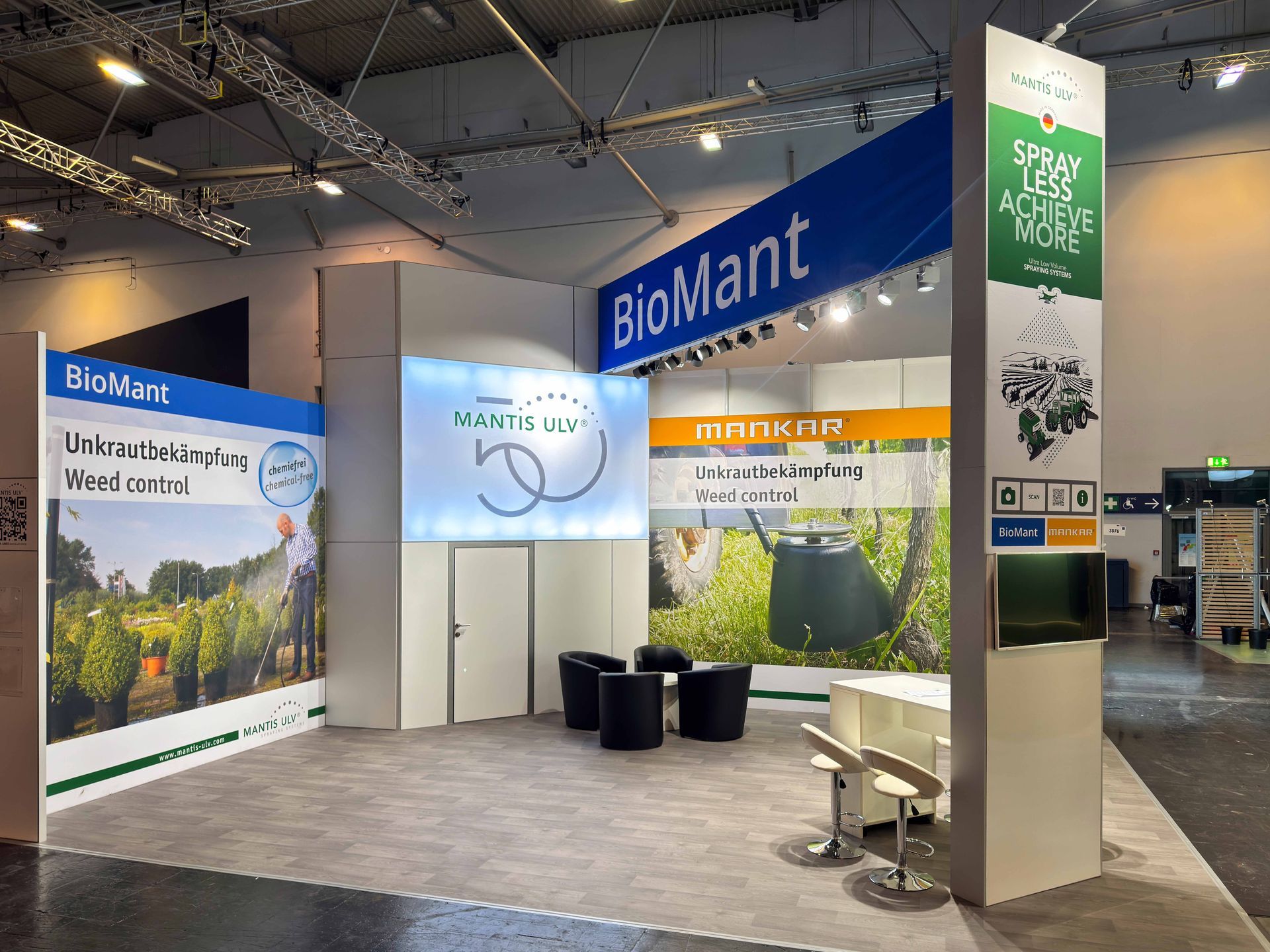 Messestand für BioMant mit blauen und grünen Paneelen, Hängeschild und Ausstellungstheken in einer Ausstellungshalle