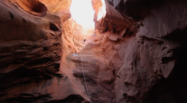 Sunlit red sandstone canyon with a narrow opening and steep rock walls