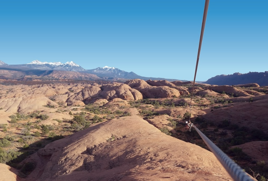 Zipline over a desert canyon with snowy mountains in the distance