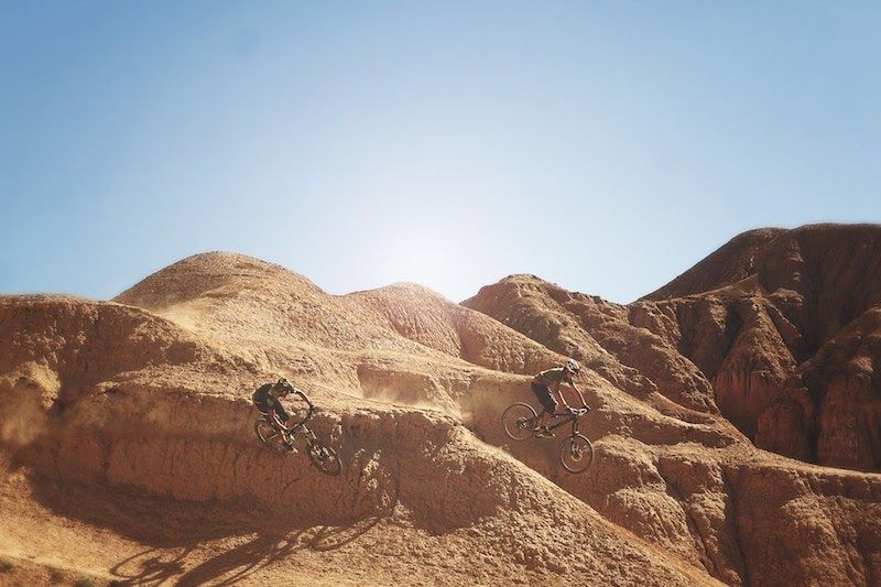Sunlit sandy desert hills beneath a clear blue sky