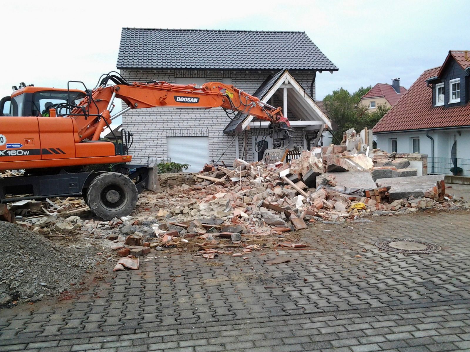 Ein großer orangefarbener Bagger zerstört ein Haus