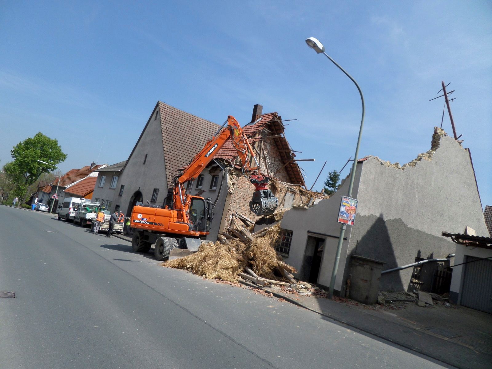Ein Bagger zerstört ein Gebäude am Straßenrand