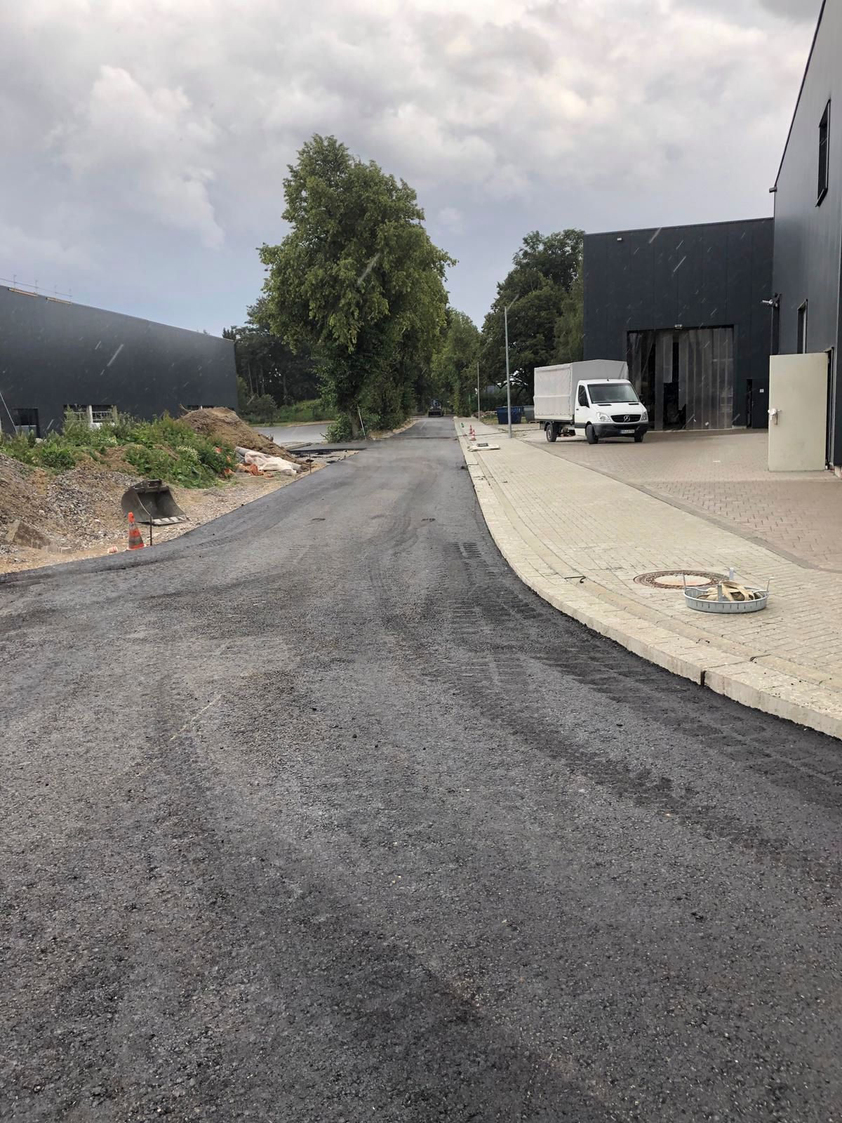 Ein weißer Lieferwagen steht am Straßenrand neben einem Gebäude.