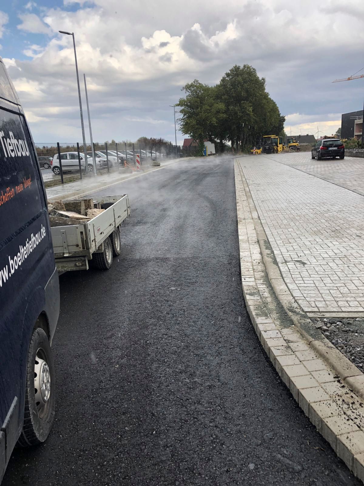 Ein Lieferwagen steht neben einem Anhänger am Straßenrand.