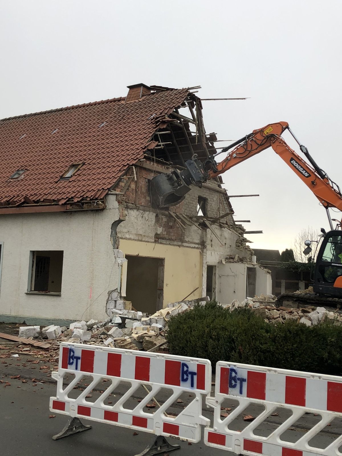 Ein Haus wird mit einem Bagger abgerissen.
