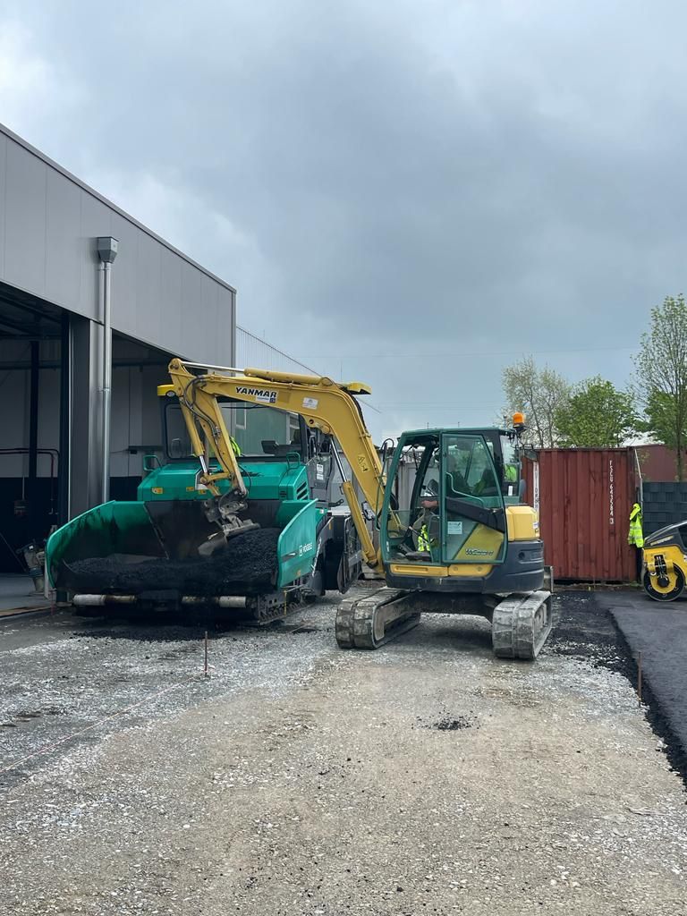 Vor einem Gebäude parken einige Baufahrzeuge.