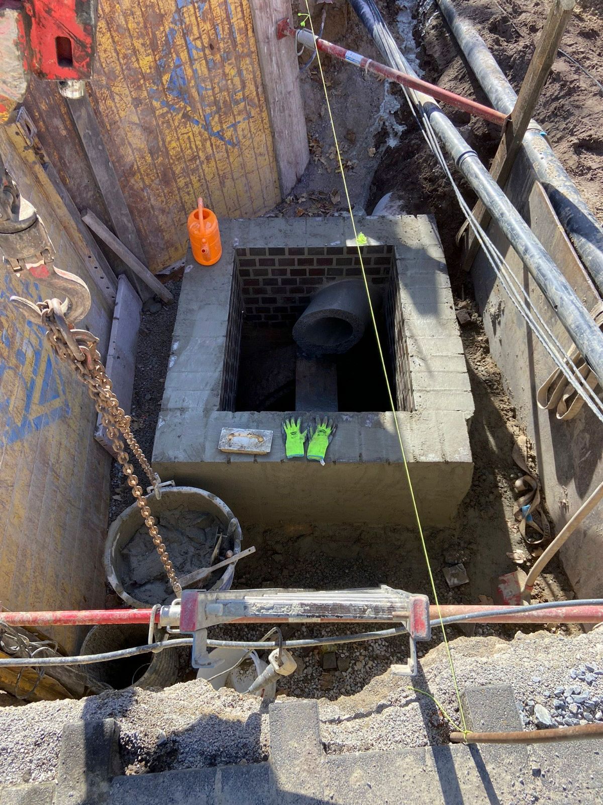 In einem Loch im Boden wird ein Schachtdeckel eingebaut.