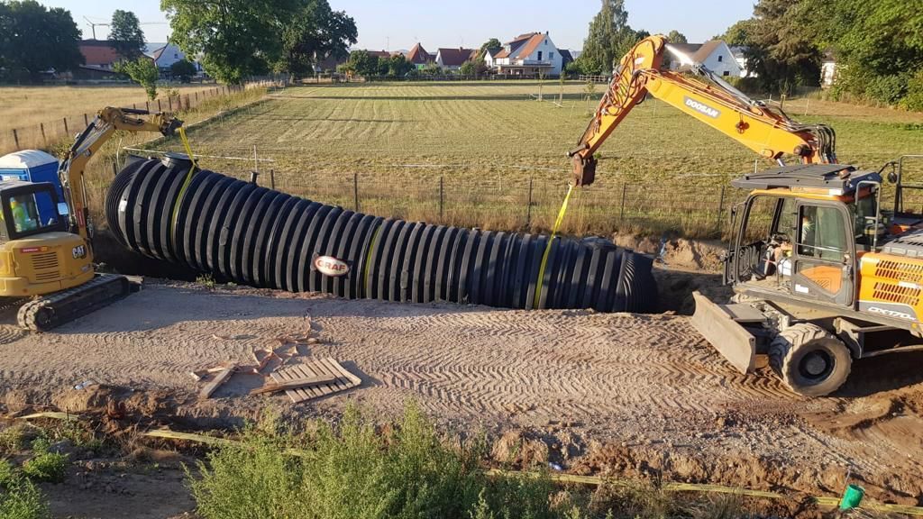 Auf einer Baustelle wird ein großes Rohr installiert.