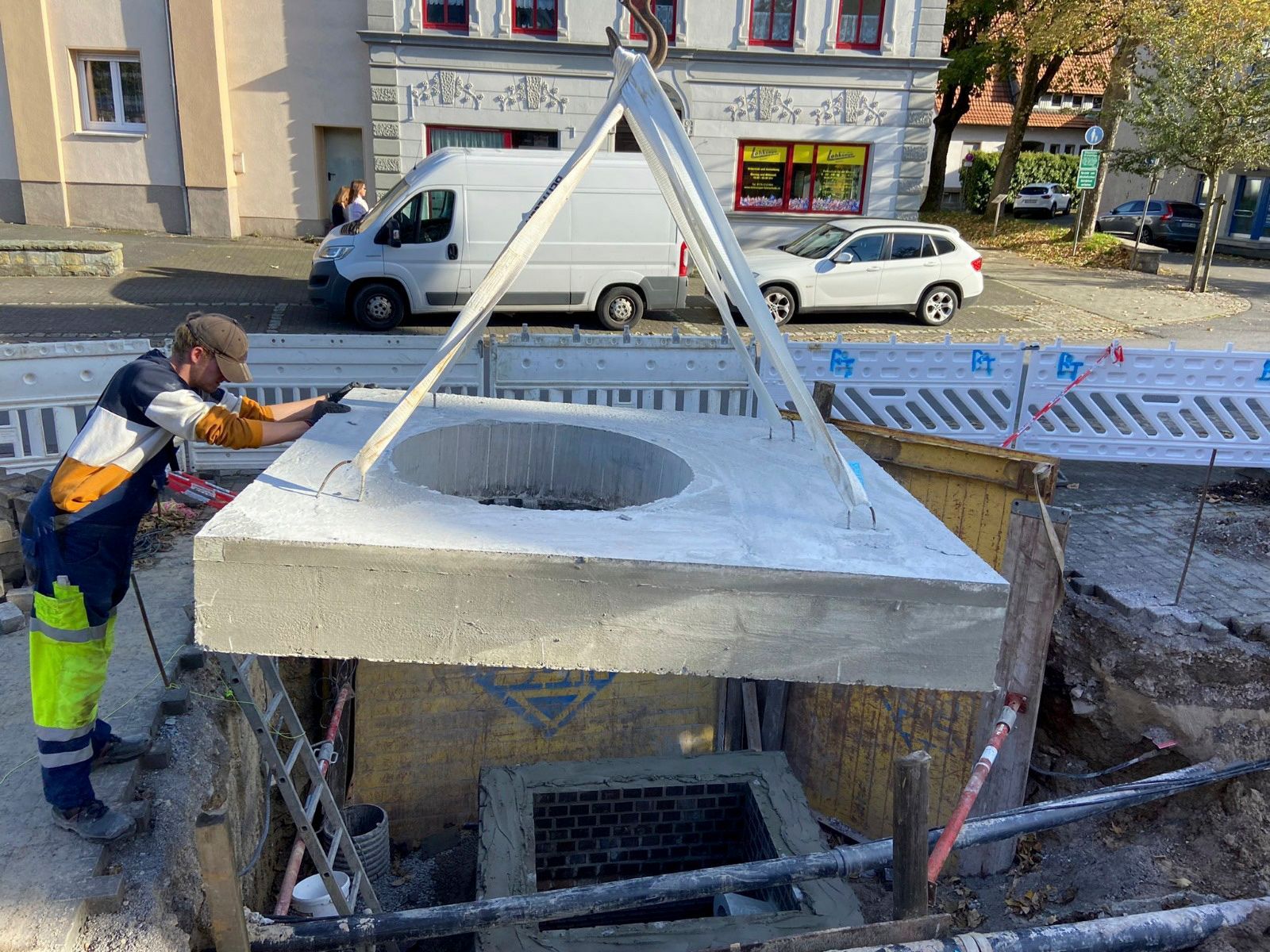 Ein Mann hebt eine Betonplatte in ein Loch im Boden.