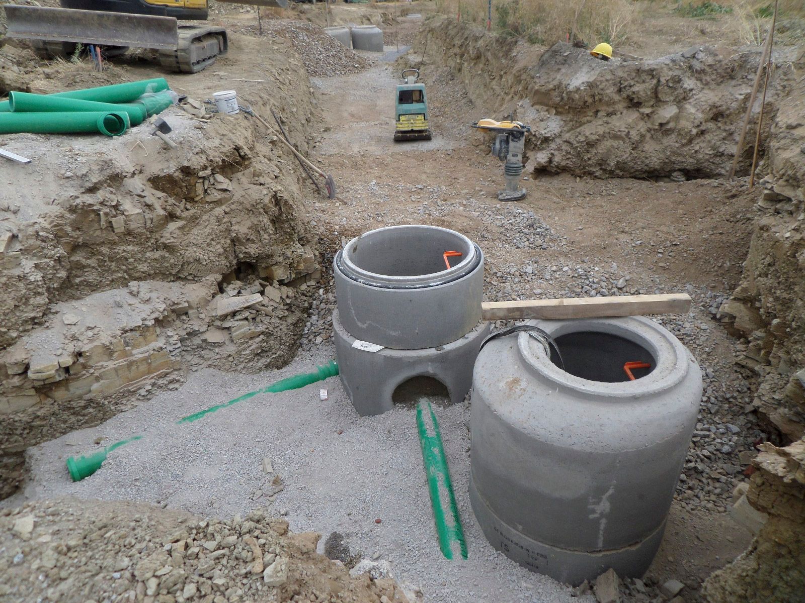 In einem Loch im Boden wird ein Schachtdeckel eingebaut.