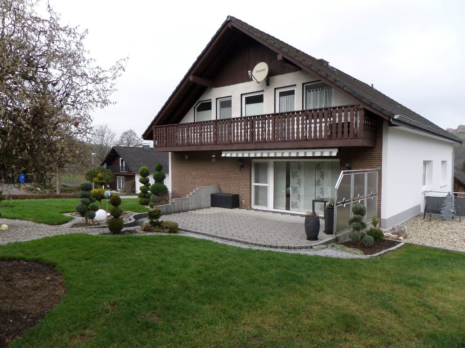 Ein großes Haus mit Balkon und großer Wiese davor