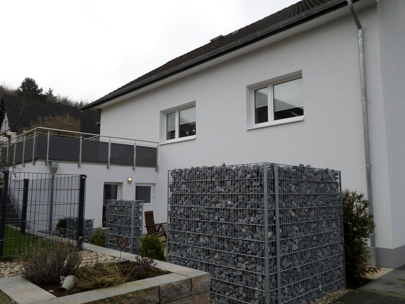 Ein weißes Haus mit Zaun und Balkon