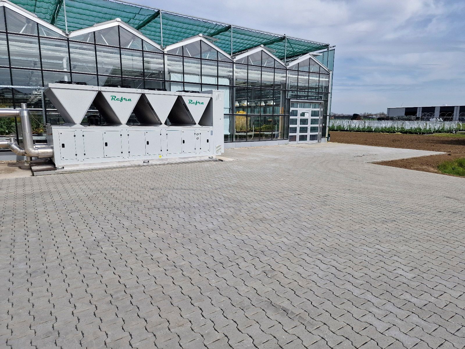 Ein großes Gewächshaus mit einer gepflasterten Auffahrt davor.