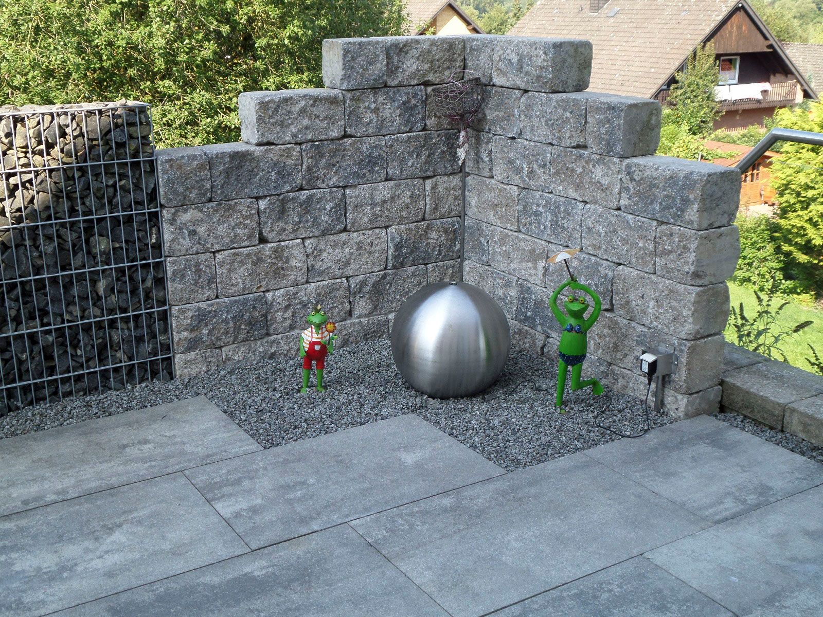 Eine Terrasse mit einer Ziegelmauer und einer Edelstahlkugel