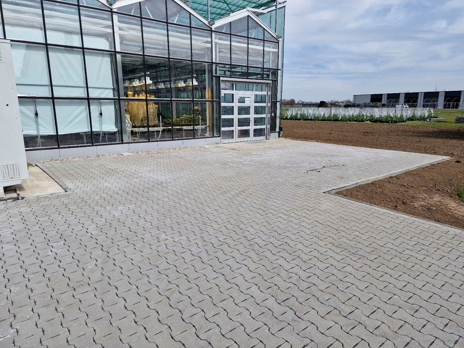 Ein großes Gewächshaus mit einer gepflasterten Auffahrt davor.