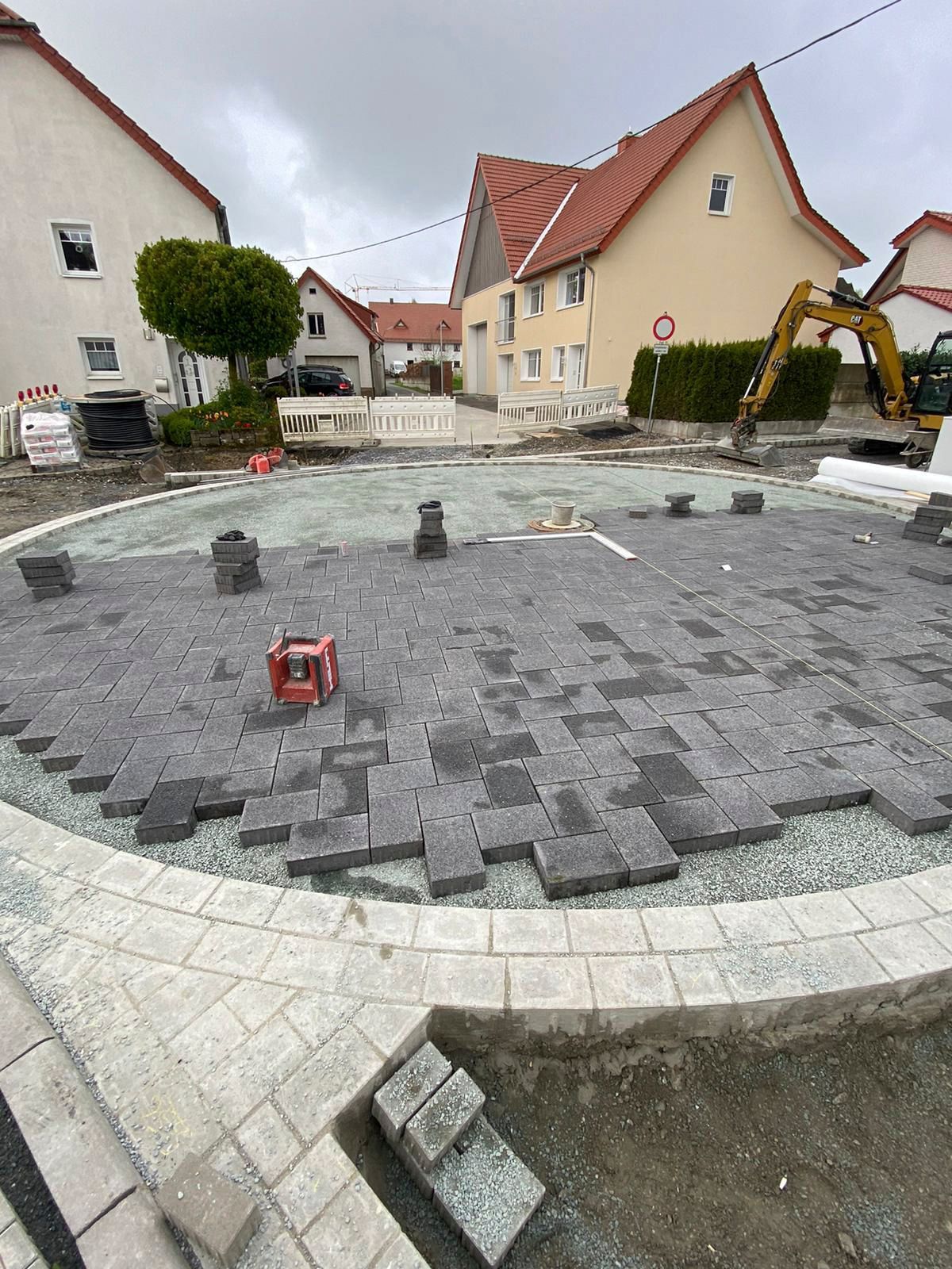 Vor einem Haus wird ein Kreis aus Ziegeln errichtet.