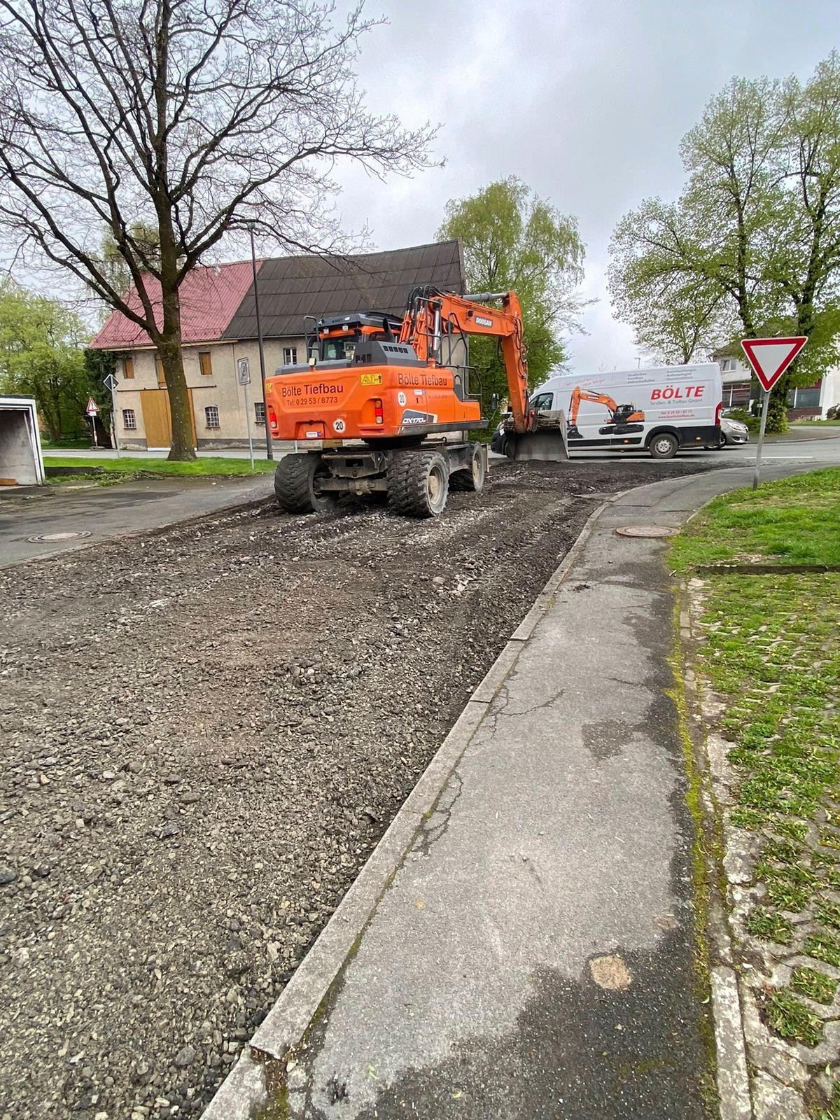 Ein Baufahrzeug fährt eine Straße neben einem Gehweg entlang.