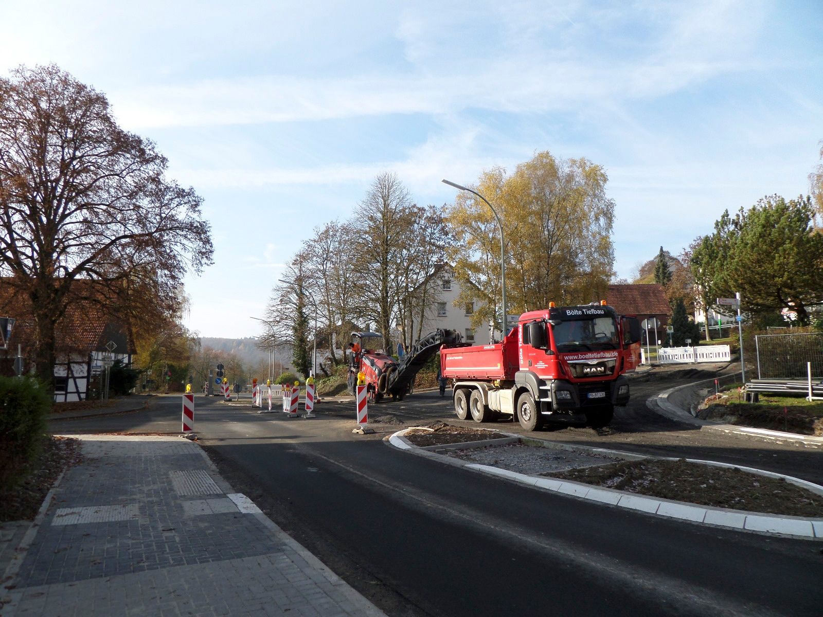 Ein roter Muldenkipper fährt eine Straße entlang.