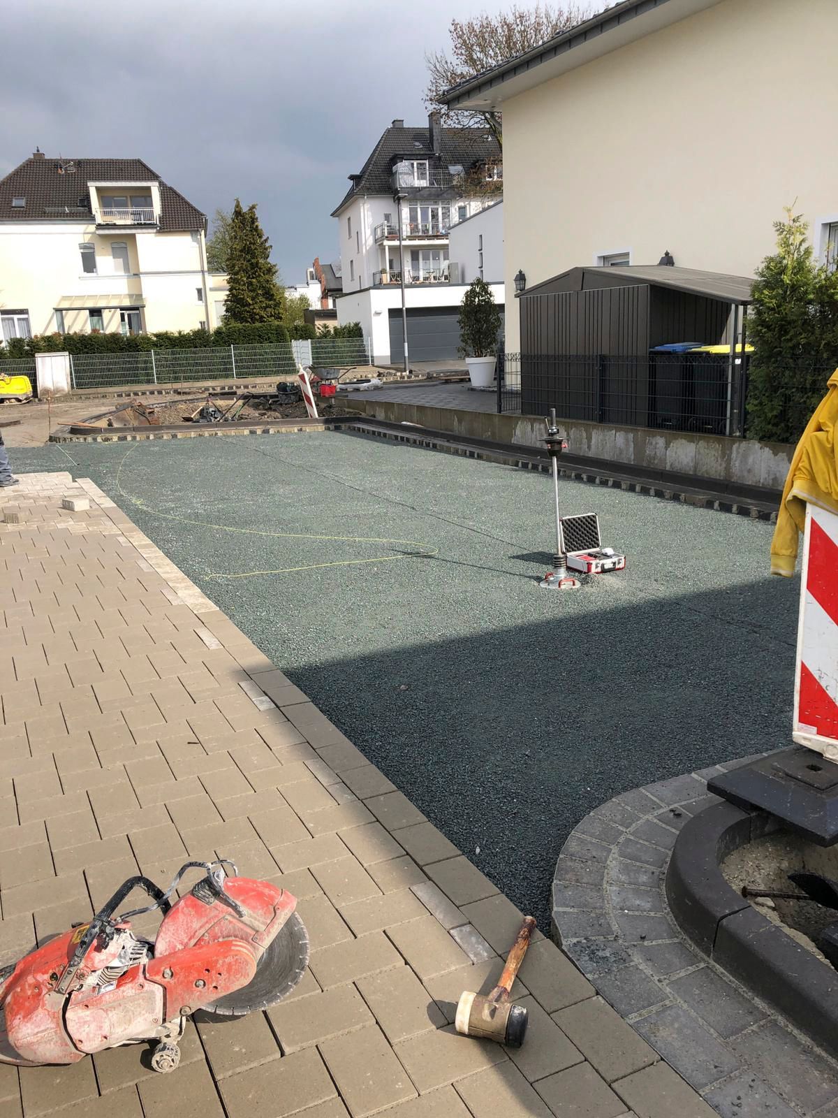 Auf dem Gehweg vor einem Gebäude liegt ein Hammer.