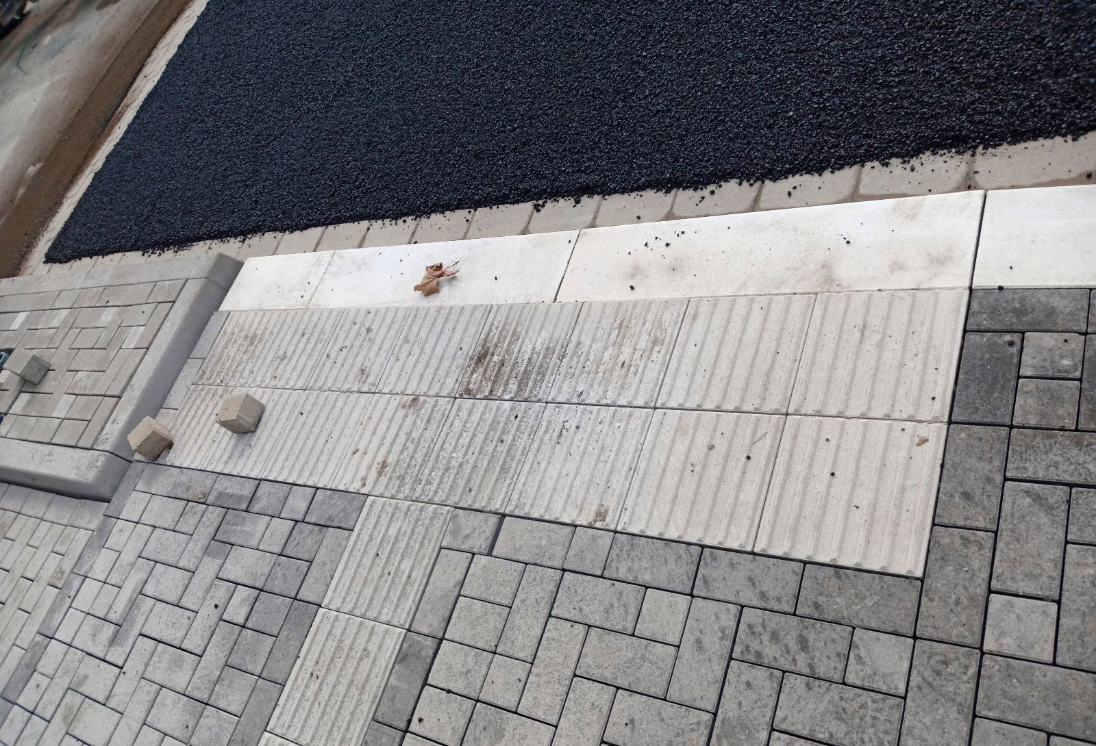 Ein Ziegelweg mit schwarzem Asphaltrand