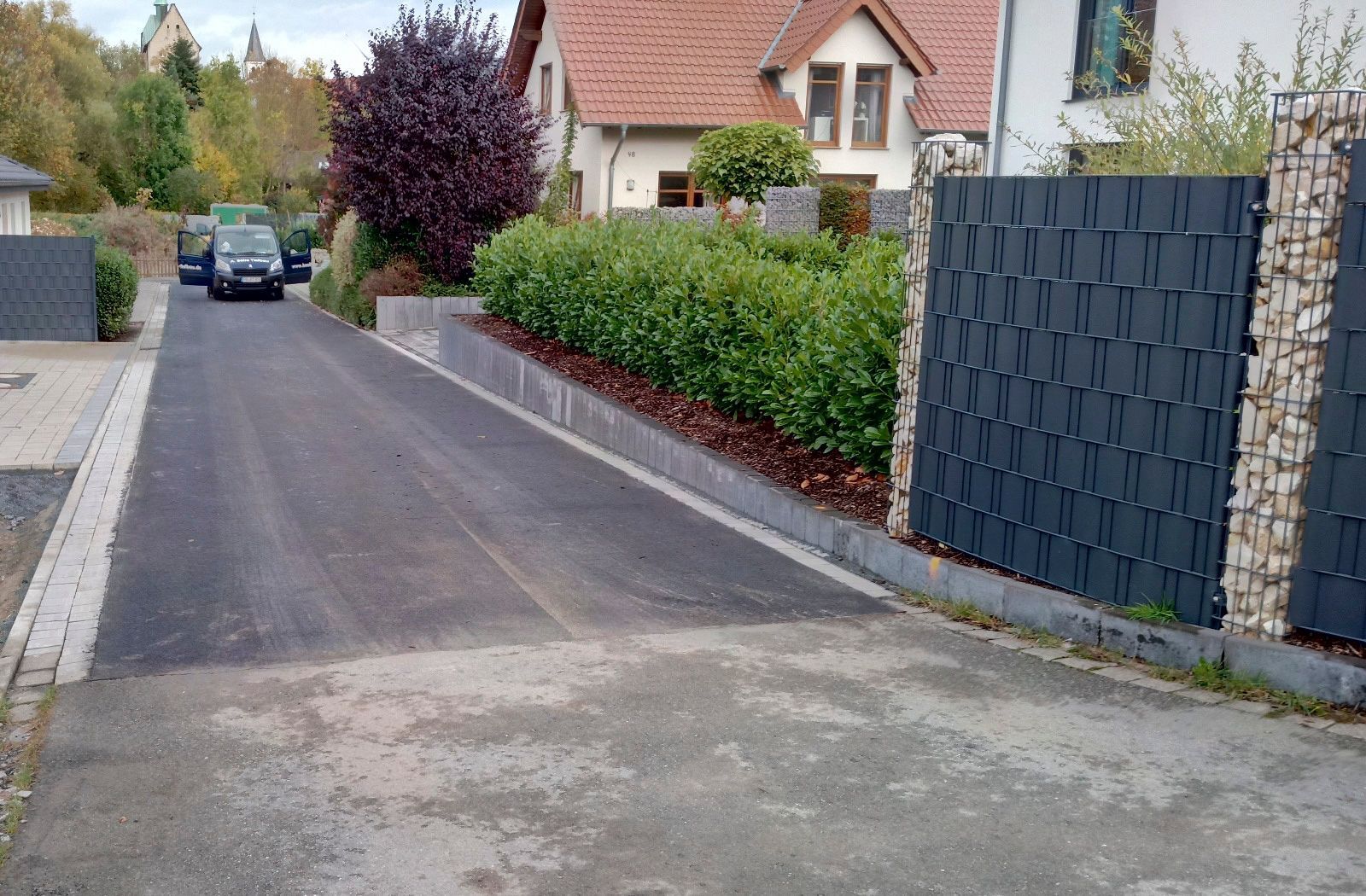 Ein Auto ist am Straßenrand neben einem Zaun geparkt.