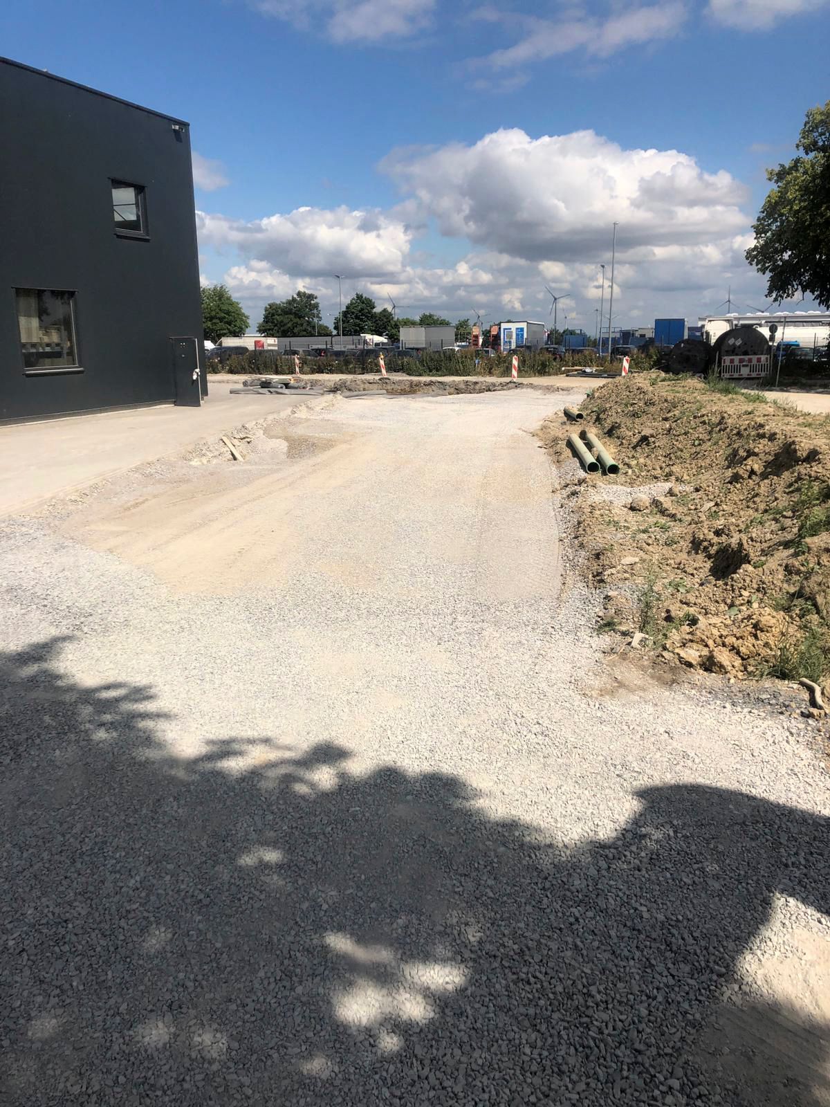 Eine unbefestigte Straße mit einem Gebäude im Hintergrund und einem blauen Himmel mit Wolken.