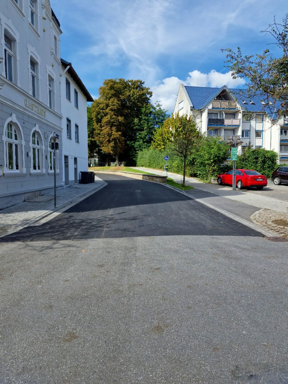 Ein rotes Auto parkt am Straßenrand vor einem Gebäude.