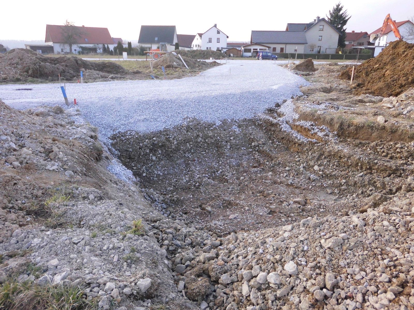 Eine Baustelle mit viel Kies und Häusern im Hintergrund