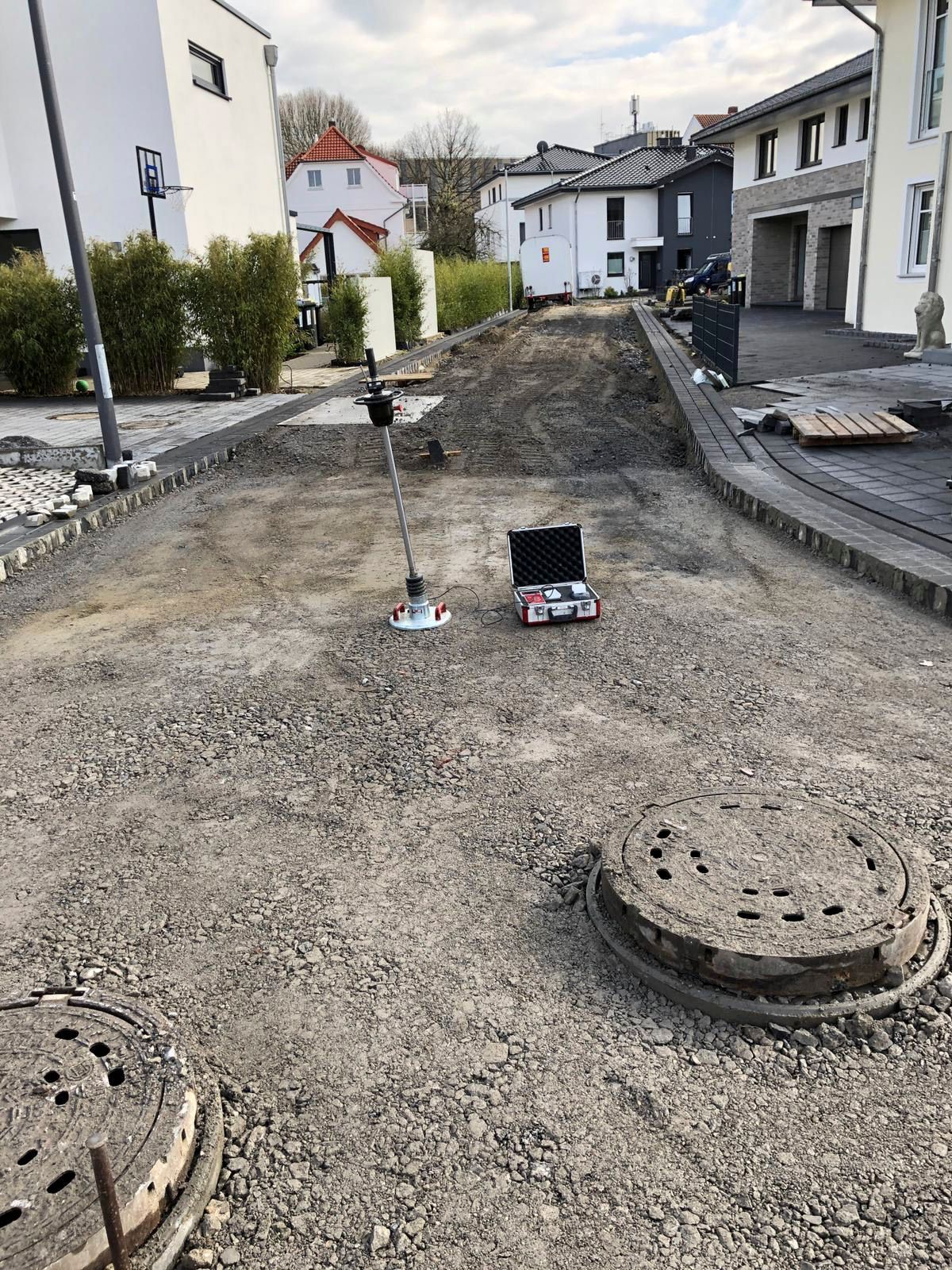 Ein Laptop liegt neben einem Gullydeckel auf dem Boden.