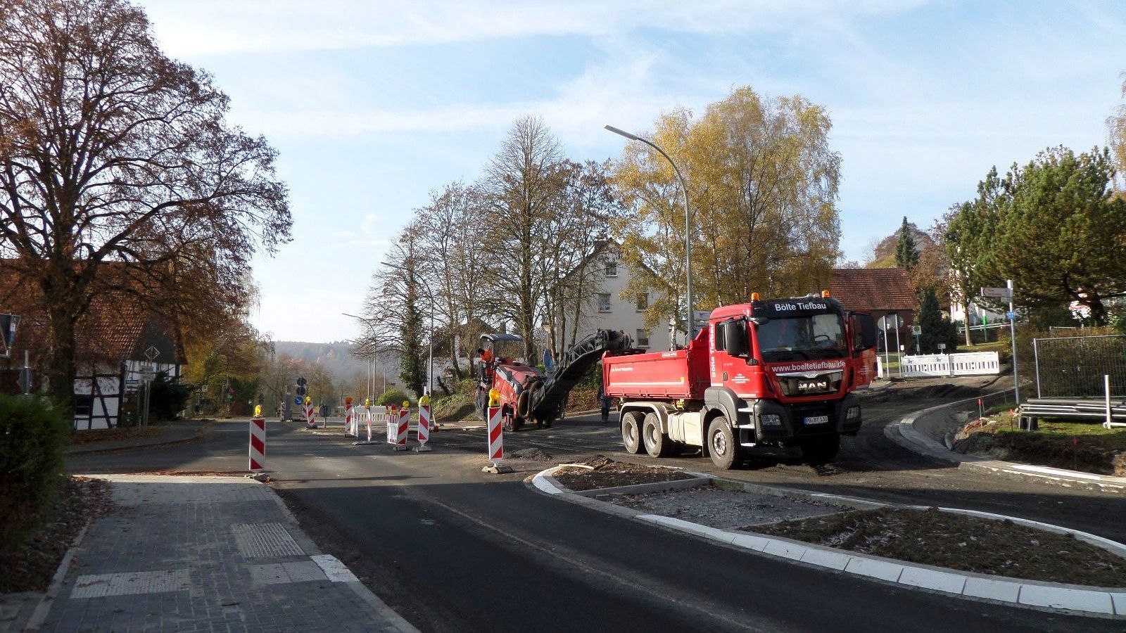 Ein roter Muldenkipper fährt eine Straße entlang.