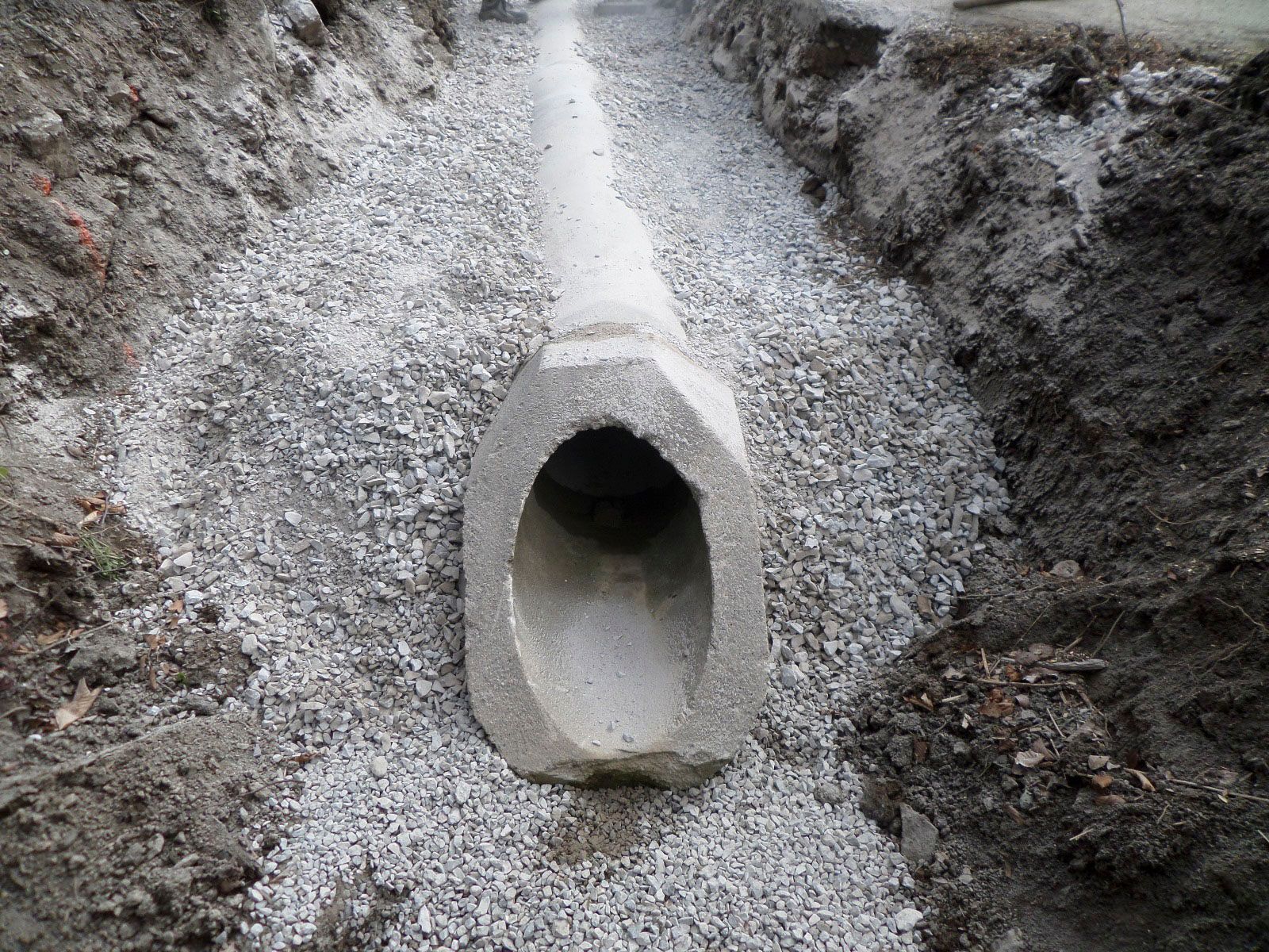 In einem Graben wird ein Betonrohr verlegt.