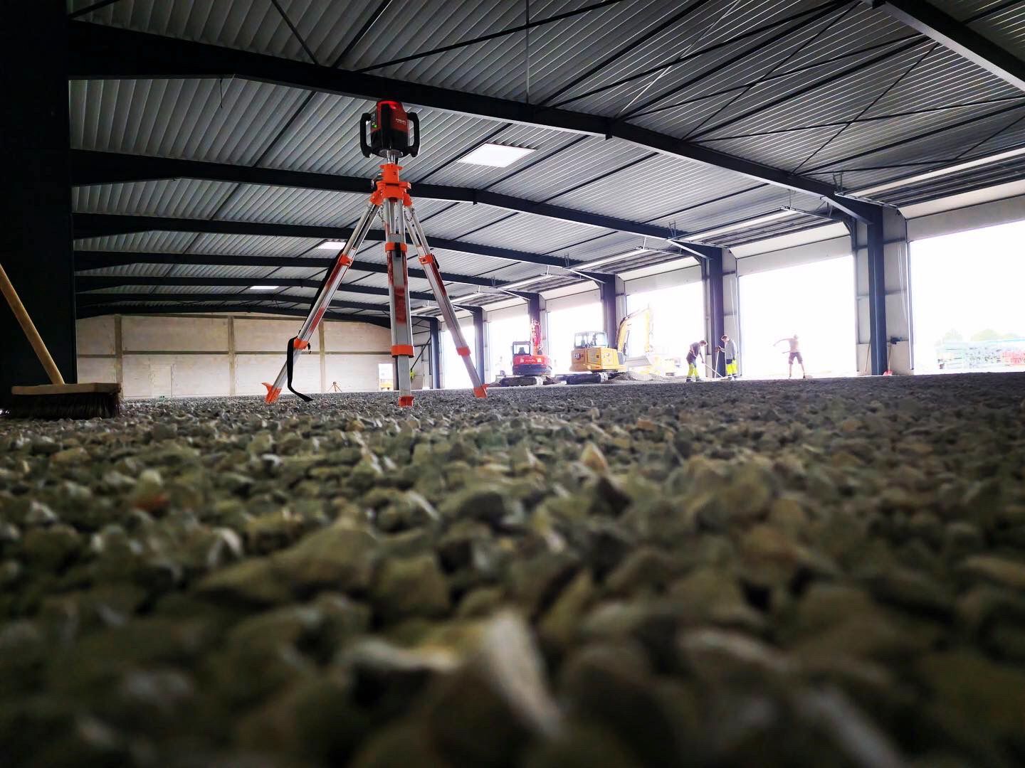 Im Inneren eines Gebäudes steht ein Stativ auf einem Kieshaufen.