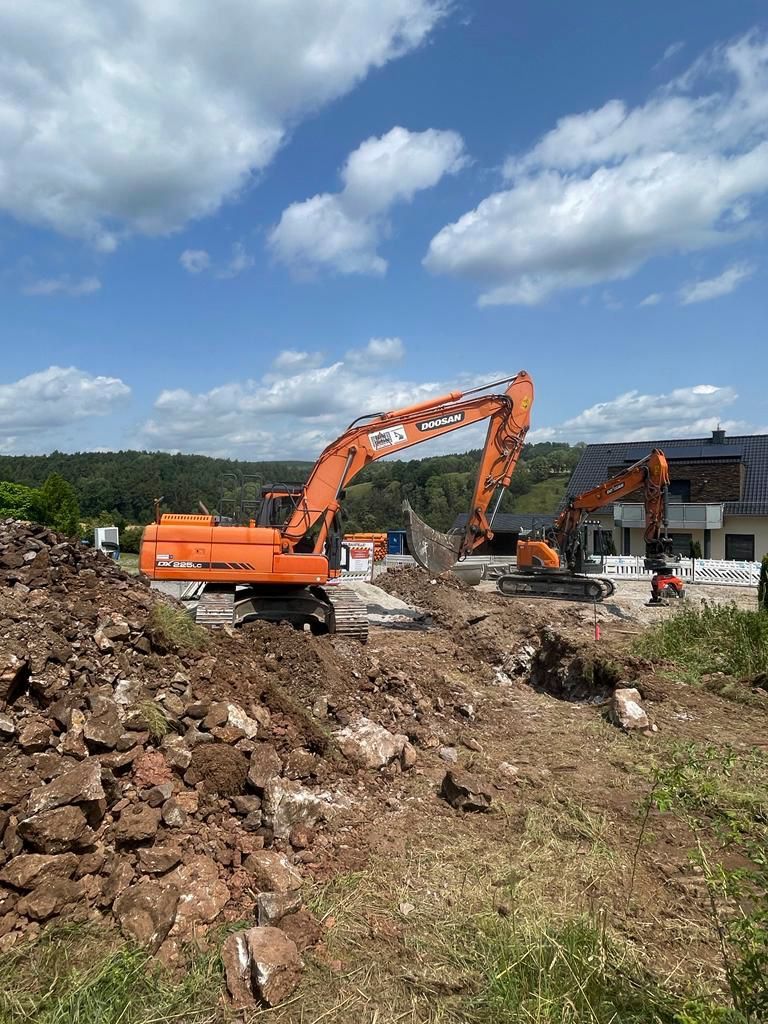 Ein großer orangefarbener Bagger arbeitet auf einer Baustelle.