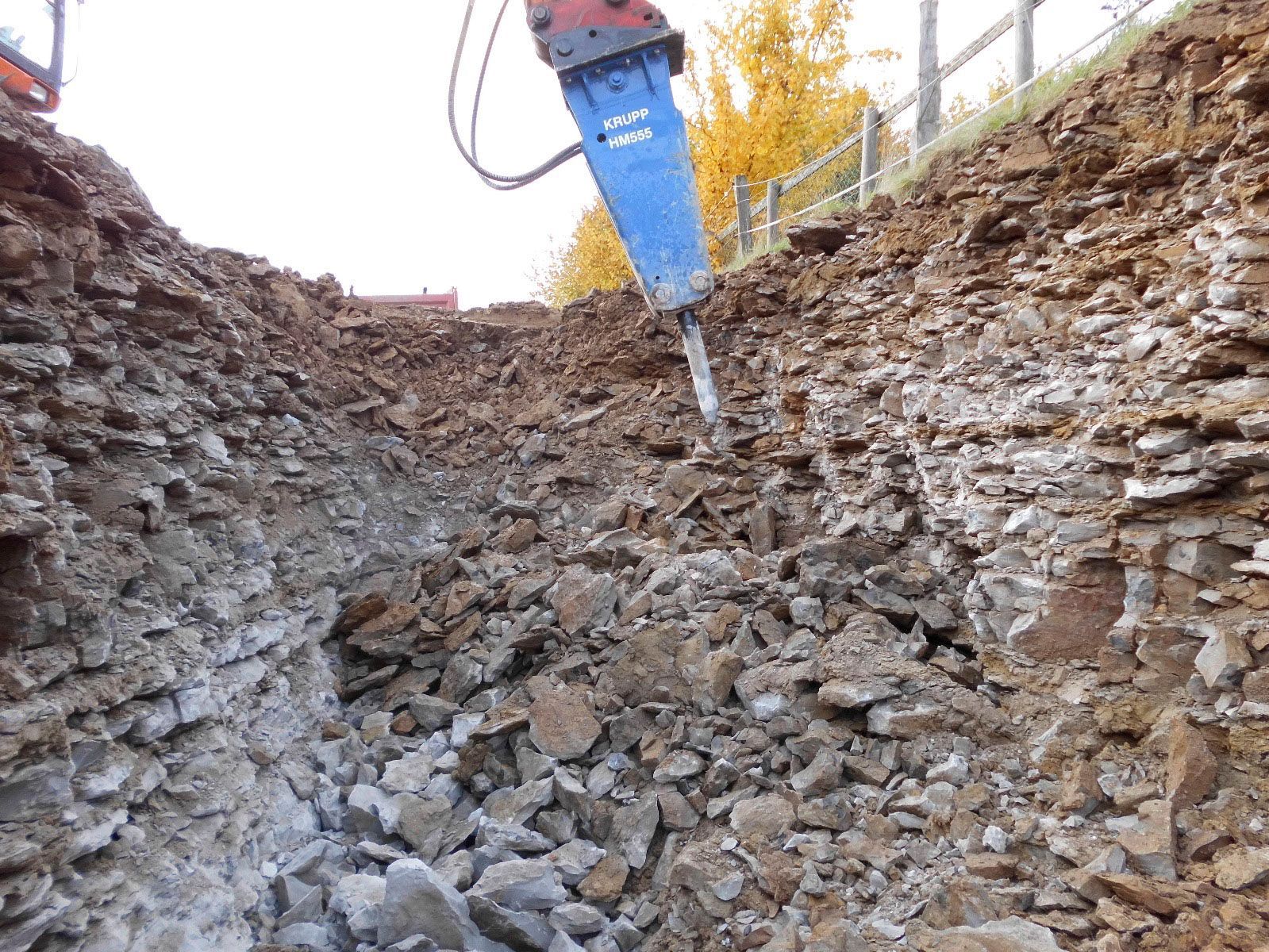 Eine Maschine zerkleinert Steine in einem Erdhaufen.