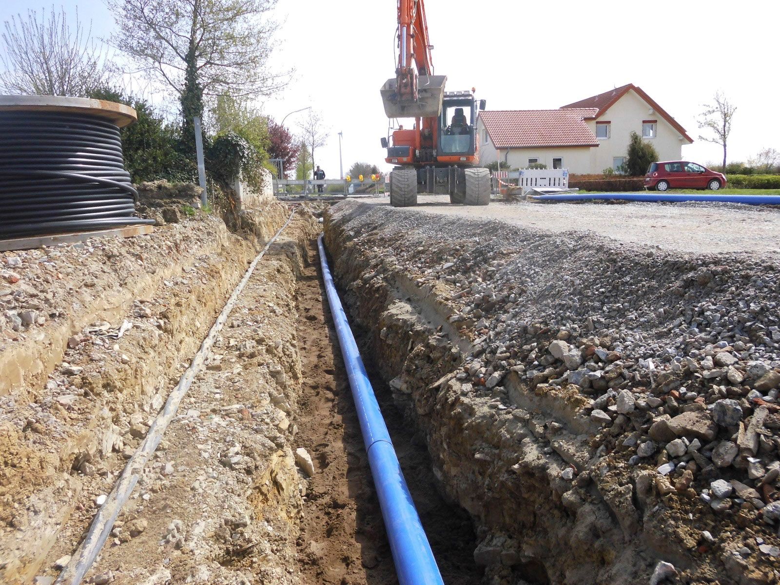 Ein blaues Rohr wird im Boden in der Nähe eines Hauses installiert