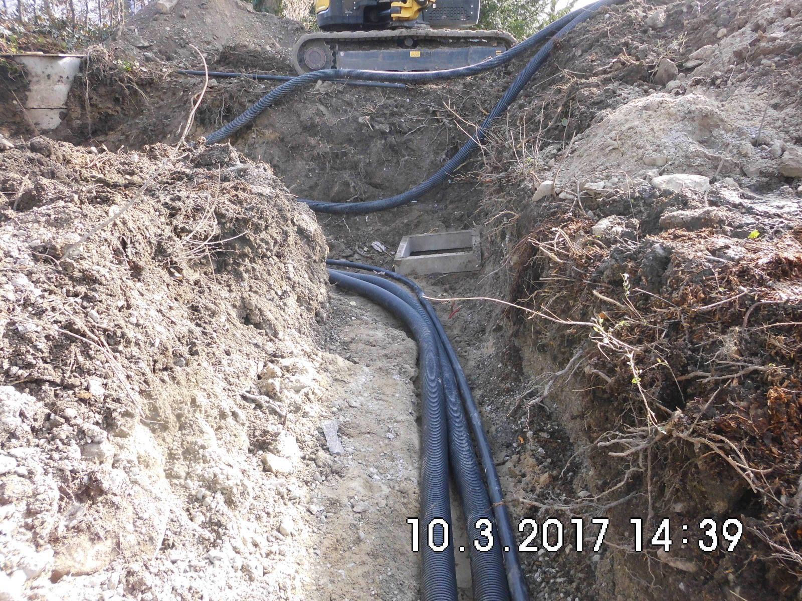 Ein Haufen Rohre liegt in einem Graben im Dreck.